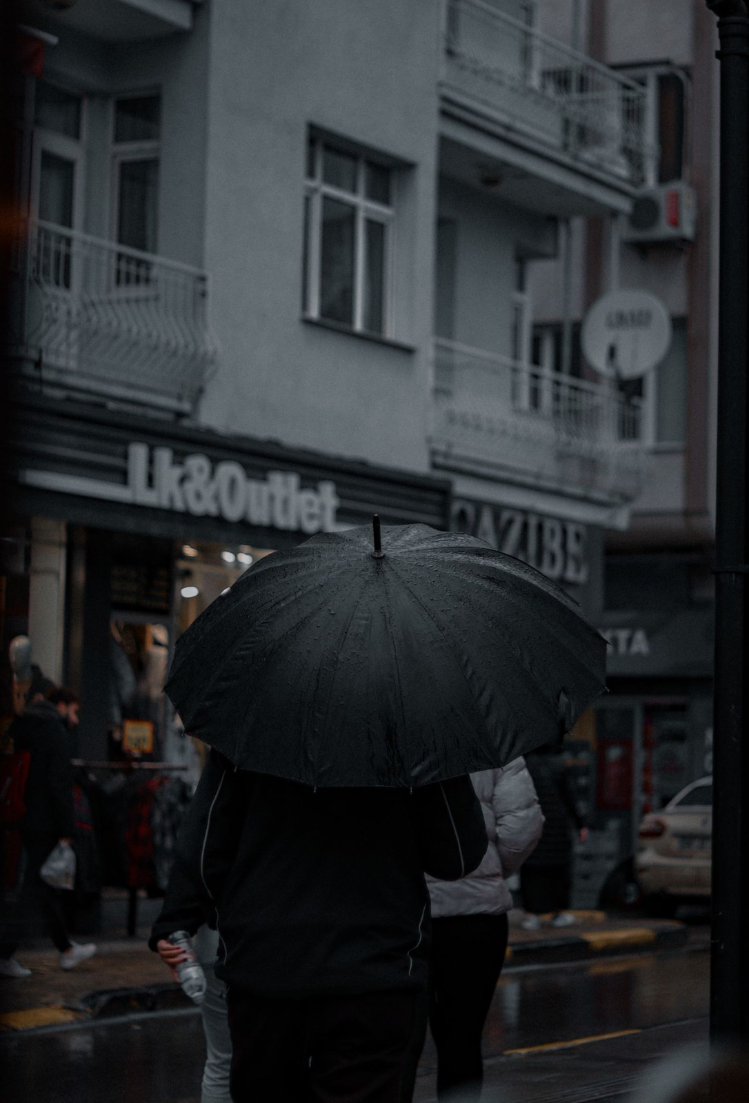 Fußgänger mit Regenschirm auf einer nassen Stadtstraße