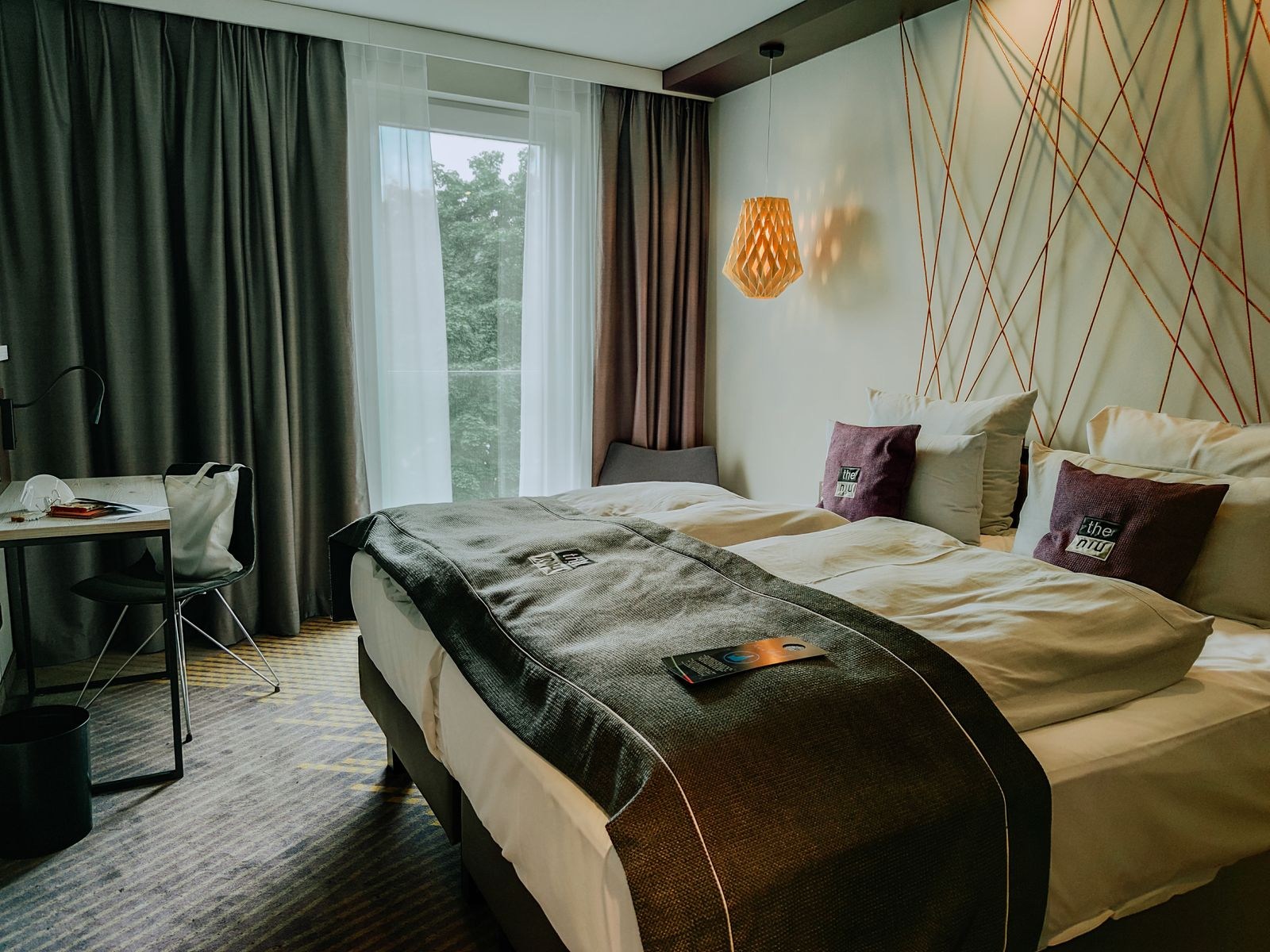 Hotelzimmer mit Bett, Fenster und kleinem Arbeitsbereich